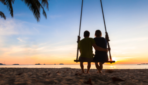 Couple on a swing watching the sunset at the beach