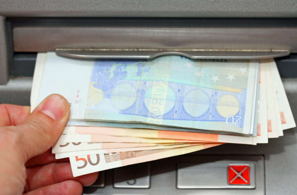 Hand withdrawing euros from an ATM