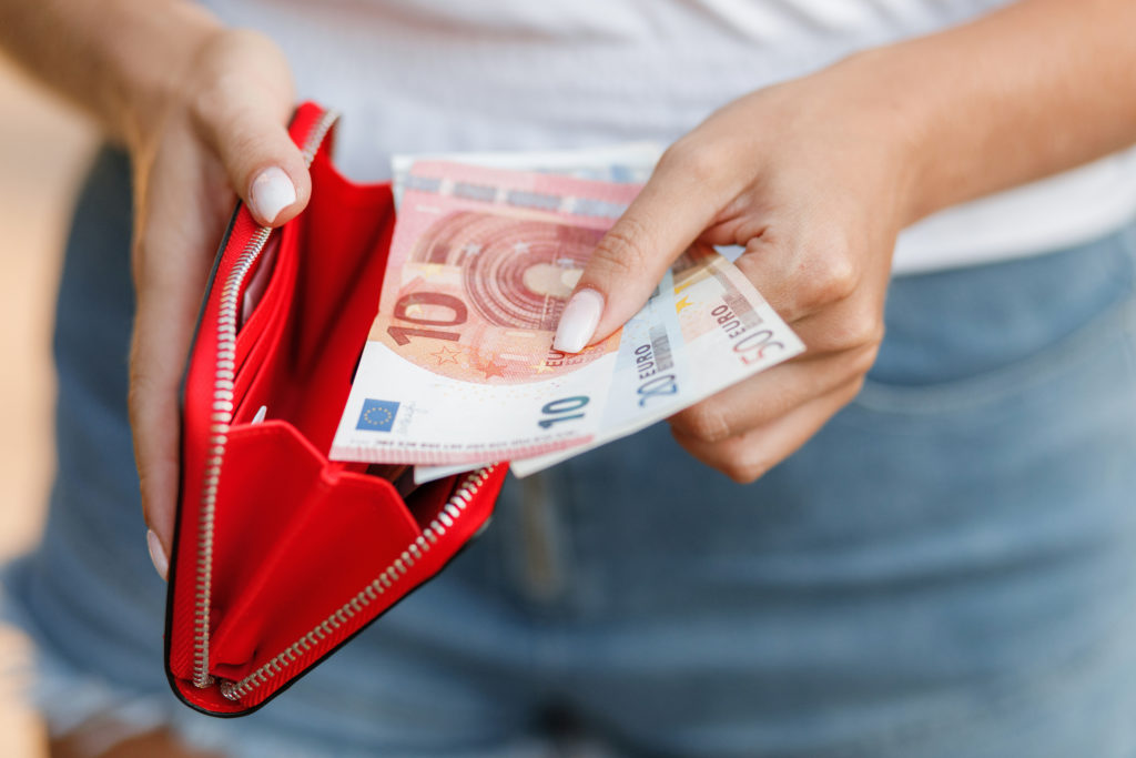 Close-up of woman taking euros out of a red wallet